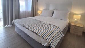 A hotel room with a large bed, a bedside table with a lamp, an air conditioning unit, and a window with curtains. - Villa Zanic (Podstrana)