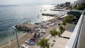 A beach with clear waters, sun loungers, umbrellas, and a rocky shoreline. - Villa Zanic (Podstrana)