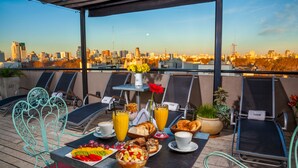 Une terrasse sur le toit, aménagée avec des tables, des chaises et offrant une vue panoramique sur la ville.