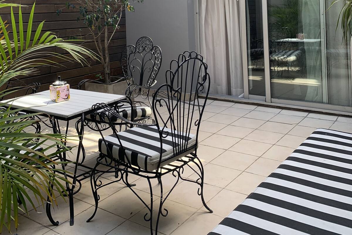 A patio with a table and chairs, a potted plant, and a sliding glass door.