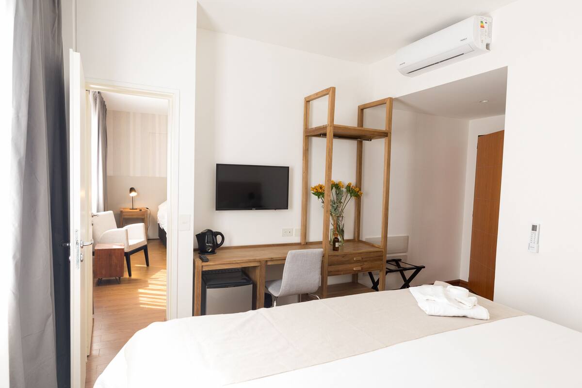 A hotel room with a bed, a desk with a chair, a TV, and a mirror.