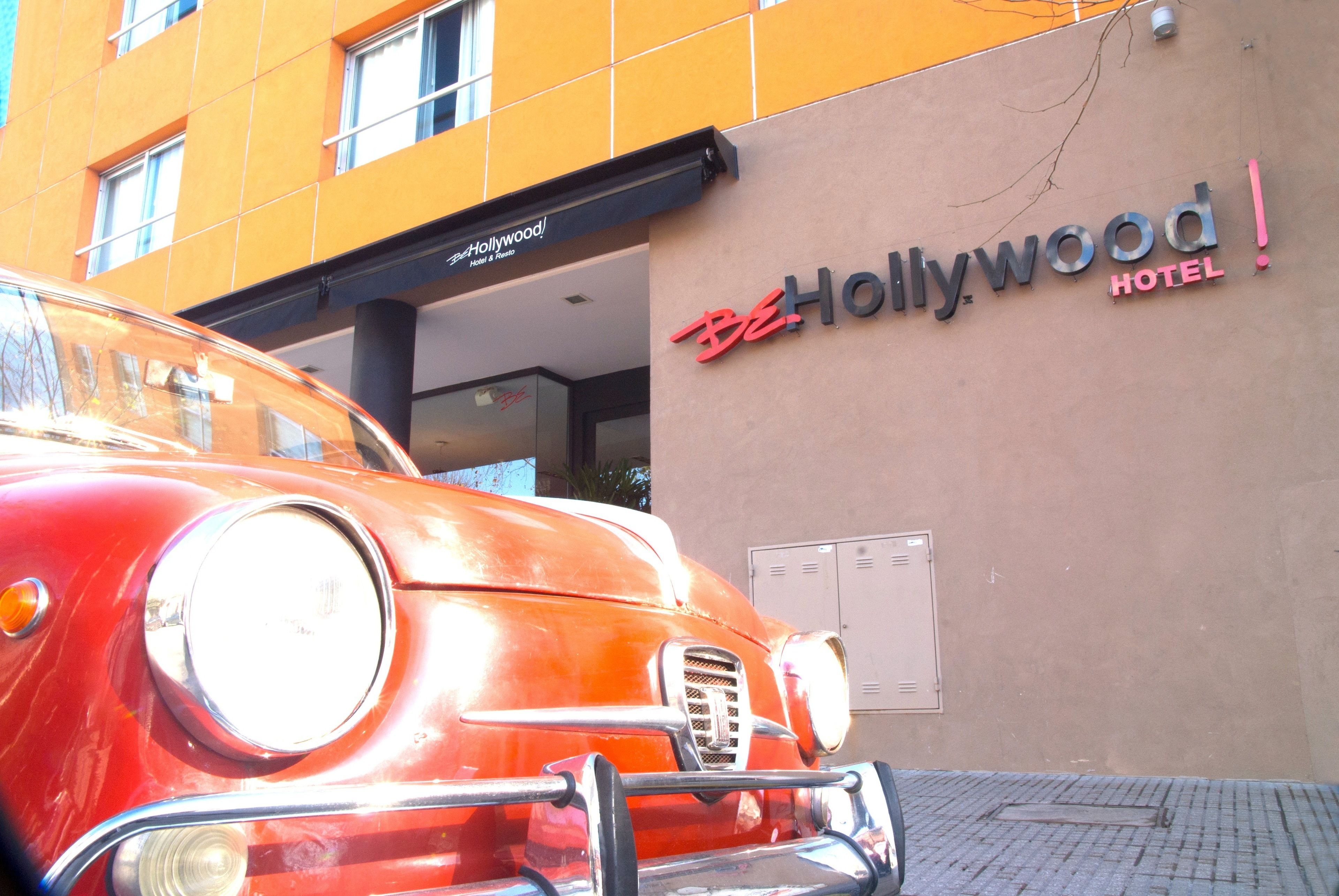 A vintage car parked in front of the BeHollywood Hotel.