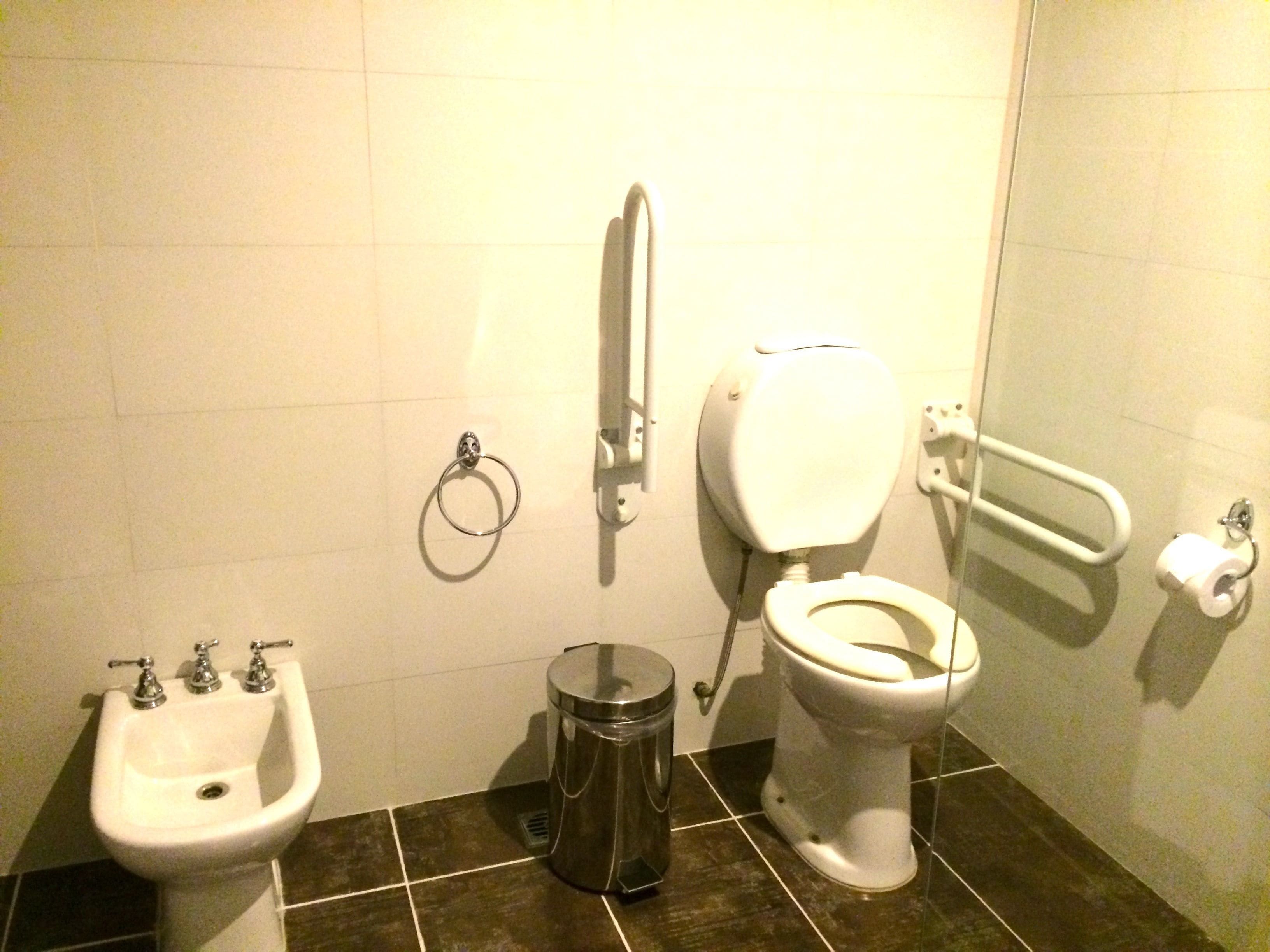 Un baño con lavabo, inodoro, bidé y cubo de basura.