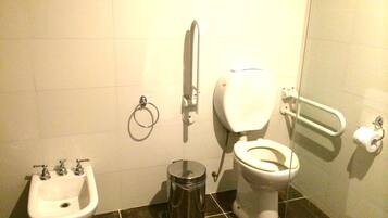 Un baño con lavabo, inodoro, bidé y cubo de basura.