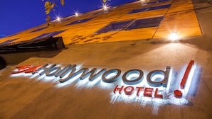 L’enseigne de l’hôtel Hollywood, illuminée la nuit, offre une vue dégagée sur la façade de l’immeuble et les arbres environnants.