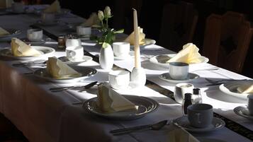 Una mesa lista para una comida, con platos, vasos y una vela.