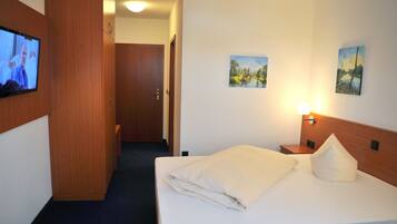 A hotel room with a bed, a TV on the wall, and two paintings.