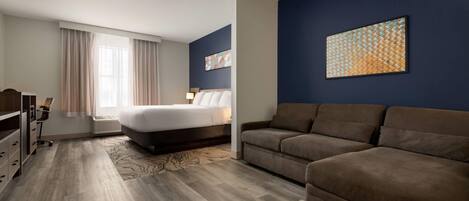 A hotel room with a bed, a sofa, a desk, and a chair.