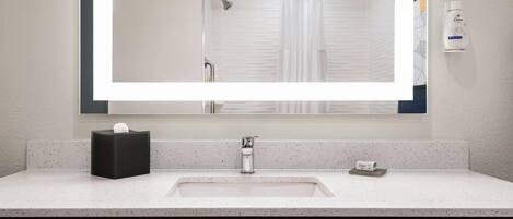 A bathroom with a white sink, a mirror, a towel rack, and a hand soap dispenser.