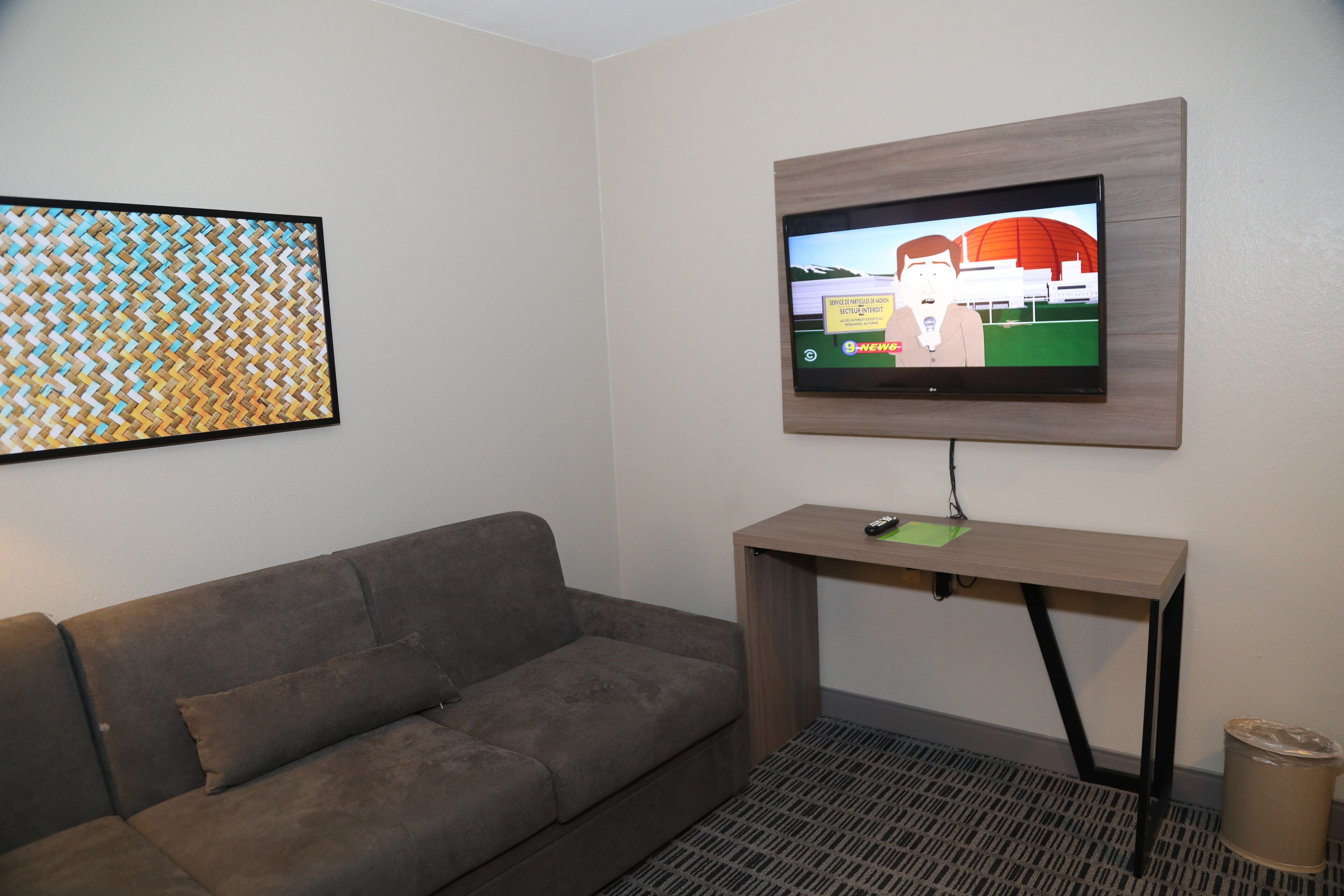 A modern living room with a gray sofa, a mounted TV, and a wooden console table.
