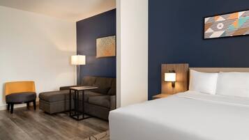 A hotel room with a bed, a sofa, a small table, and a chair.