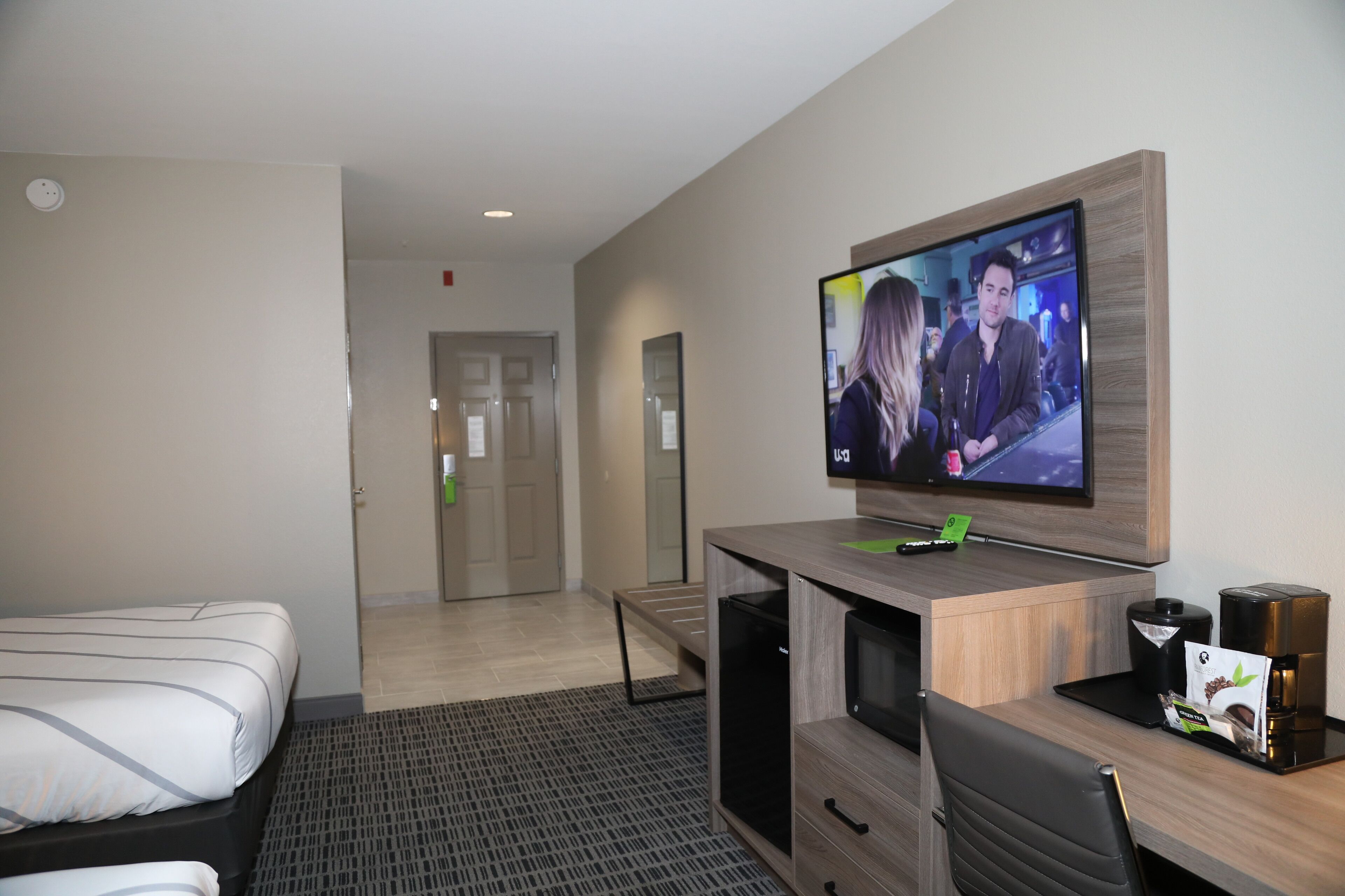 A hotel room with a bed, a desk with a computer, a television, and a coffee maker.