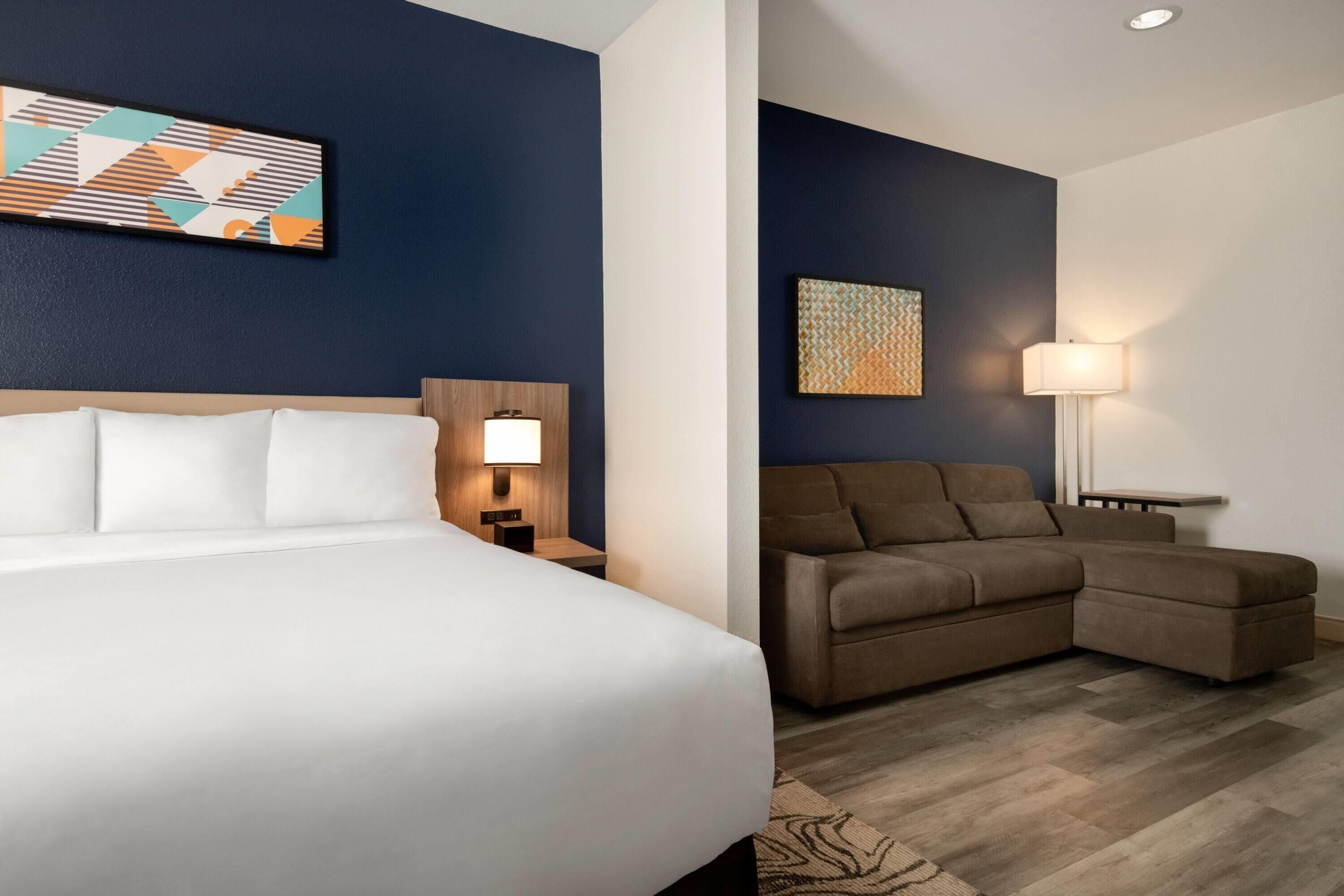 Ein Hotelzimmer mit Bett, Sofa, Nachttisch und einer Wandlampe.
