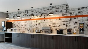 A modern kitchen with a brick-patterned backsplash, pendant lighting, and a coffee station.