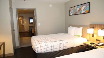 Habitación de hotel con cama, mesita de noche con lámpara, teléfono y un cuadro en la pared.