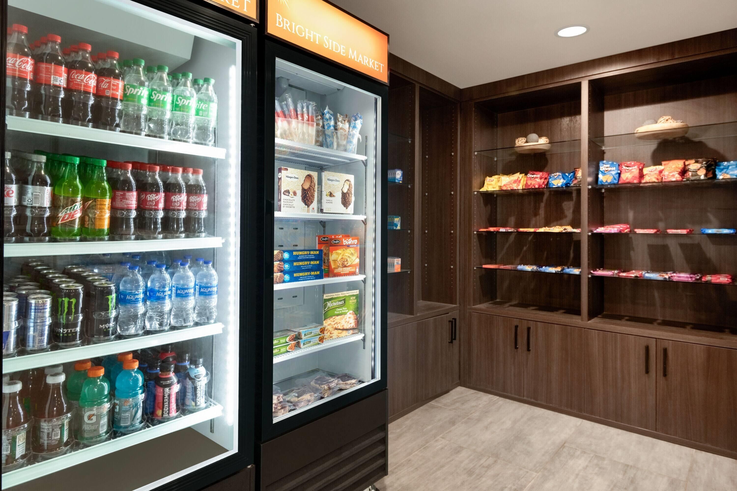 A vending machine stocked with beverages and snacks, and a wooden cabinet with packaged goods.