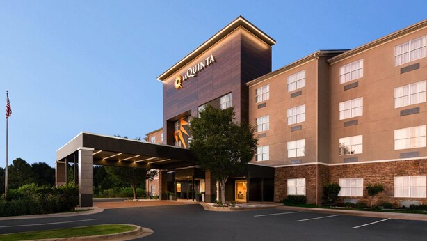 A hotel with a modern design, featuring a prominent entrance with a covered walkway and a large logo above the entrance.