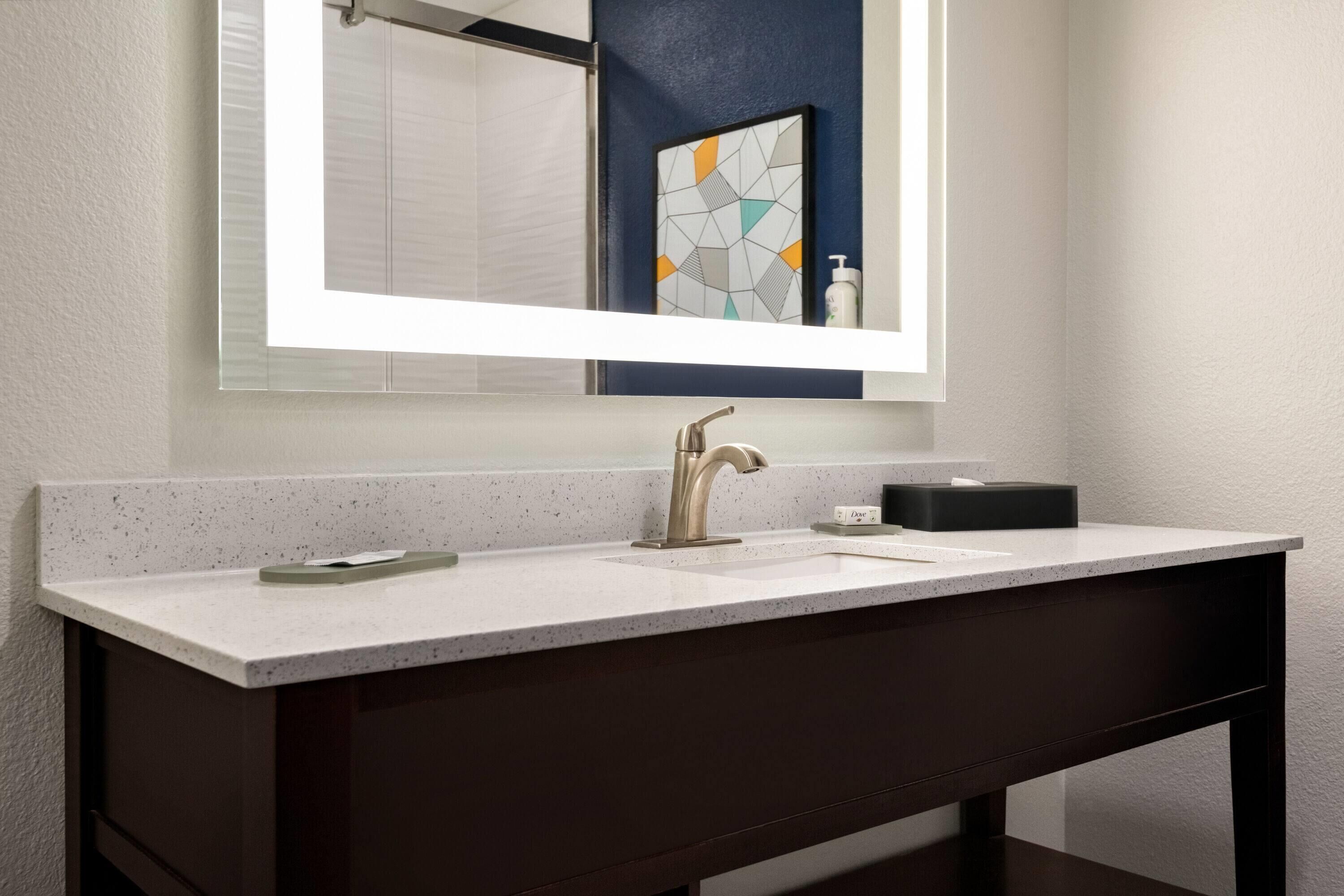 A modern bathroom with a large mirror, a double sink, and a dark vanity.