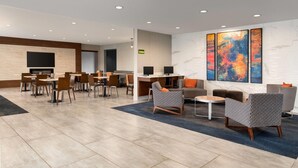 A modern hotel lobby with a dining area, seating, and artwork on the walls.