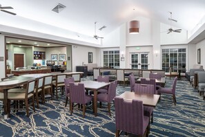 A spacious hotel lobby with multiple seating areas, including tables and chairs, and a bar area. - Homewood Suites by Hilton  Fresno Airport/Clovis, CA (Clovis)