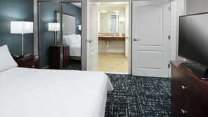 A hotel room with a bed, a television, a desk with a lamp, a mirror, and a bathroom visible through an open door. - Homewood Suites by Hilton  Fresno Airport/Clovis, CA (Clovis)