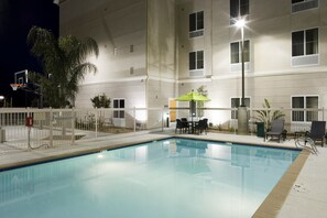 A swimming pool with a fenced area, outdoor seating, and a building in the background. - Homewood Suites by Hilton  Fresno Airport/Clovis, CA (Clovis)
