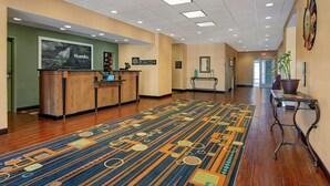A hotel lobby with a reception desk, a patterned carpet, and a clock on the wall. - Hampton Inn Lordsburg (Lordsburg)