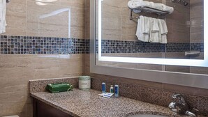 A bathroom with a granite countertop, a large mirror, and a towel rack with towels. - Rodeway Inn Meadowlands (Secaucus)