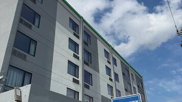 A multi-story building with a sign for the Rodeway Inn, indicating newly renovated rooms, free HBO Wi-Fi, flat-screen TVs, and a micro-fridge.