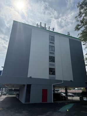 A building with a flat facade, multiple windows, and a red door at the bottom. - Rodeway Inn Meadowlands (Secaucus)