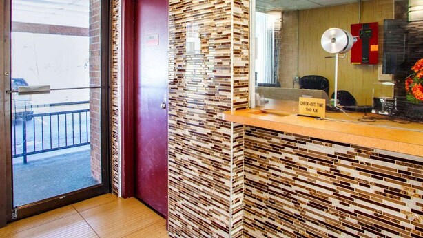 A reception area with a check-out time sign, a mirror, and a security camera. - Rodeway Inn Meadowlands (Secaucus)