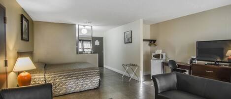 A hotel room with a bed, a desk, a television, and a sofa.