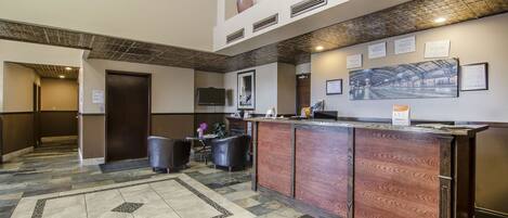 A lobby with a reception desk, seating area, and a large framed artwork on the wall.