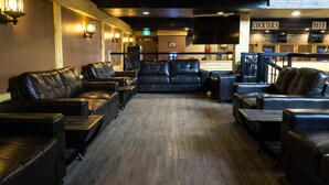 Zona de bar con asientos de cuero, un cajero automático y letreros que anuncian cócteles y cerveza.