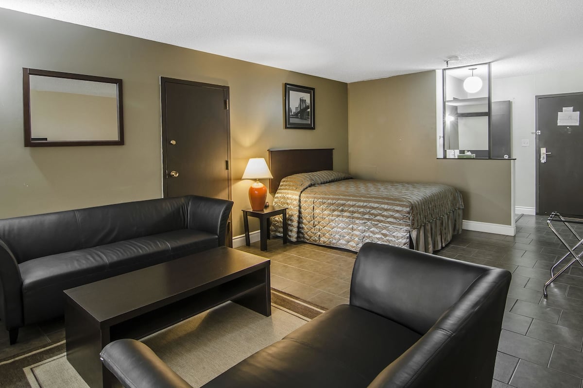 Une chambre d’hôtel avec un lit, un canapé, une table basse, une lampe et un tableau au mur.