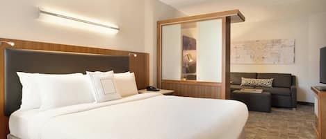 A hotel room with a large bed, a sofa, a desk, and a flat-screen TV.