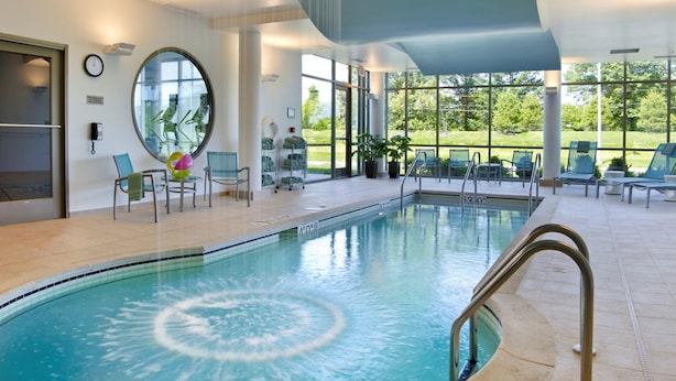 An indoor swimming pool with a circular design, large windows, and a ceiling with hanging lights.