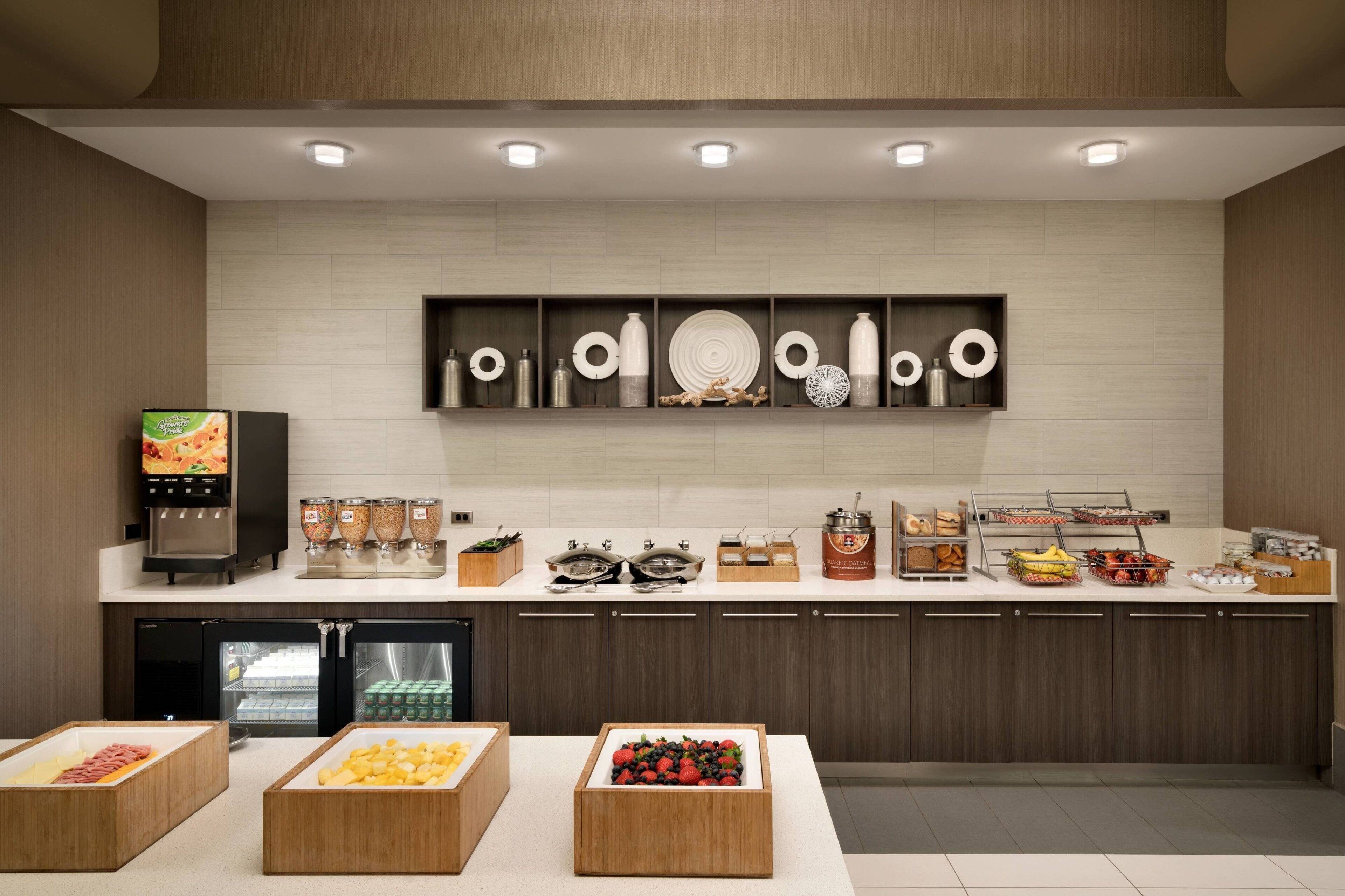 A modern kitchen with a built-in refrigerator, a coffee machine, and various food items displayed on the counter.