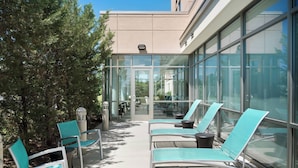 An outdoor seating area with lounge chairs and a glass wall.