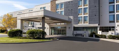 A modern hotel building with a covered entrance, large windows, and a sign reading "Springhill Suites."