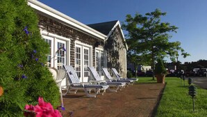 A building with a brick facade, large windows, and a row of sun loungers outside.
