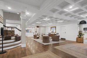 A spacious interior with a staircase, wicker furniture, and a registration sign.