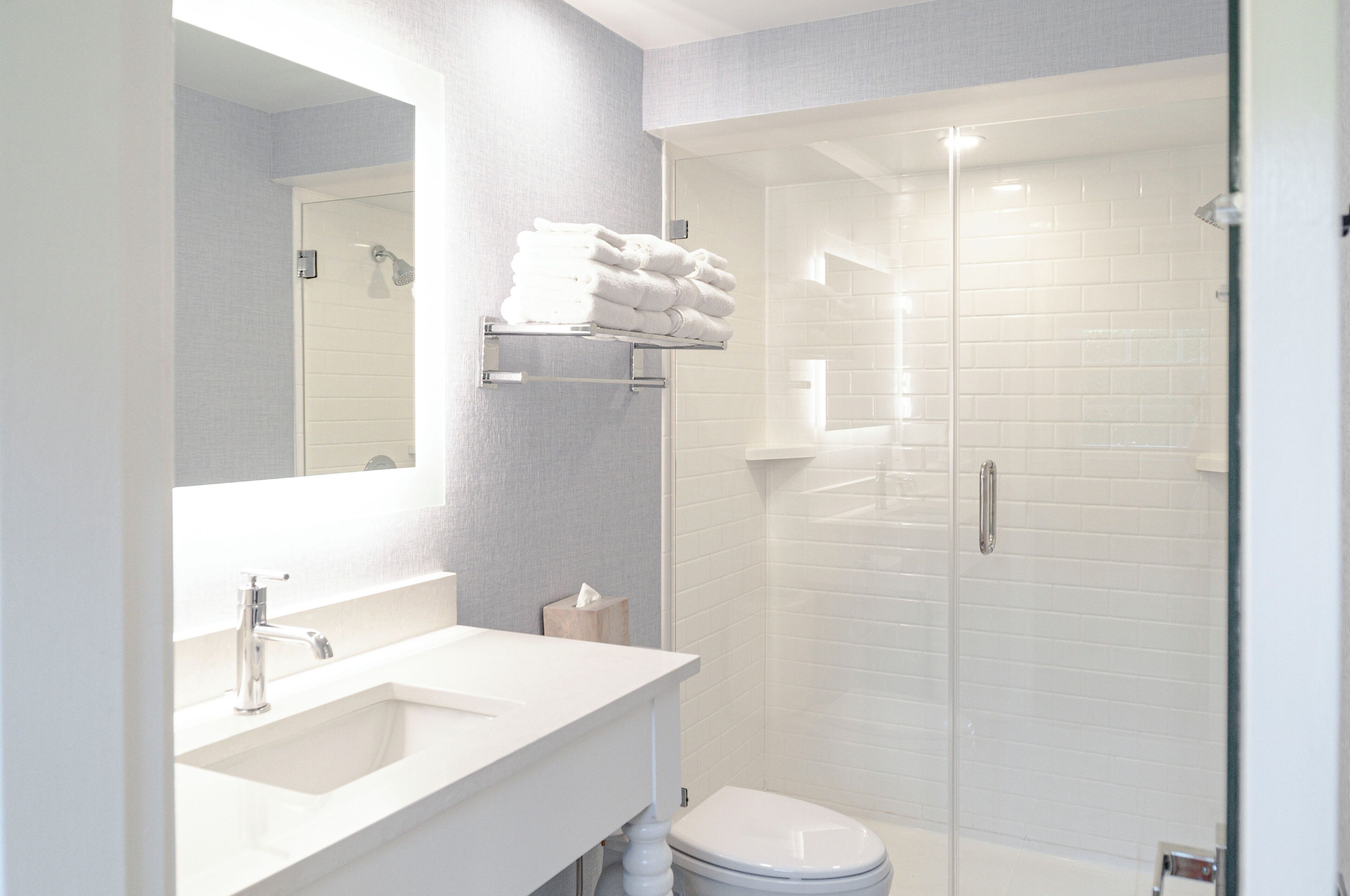 Une salle de bain moderne avec un lavabo blanc, un miroir et une douche à parois de verre.