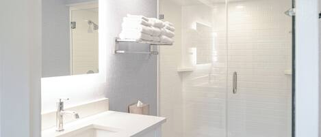 Une salle de bain moderne avec un lavabo blanc, un miroir et une douche à parois de verre.