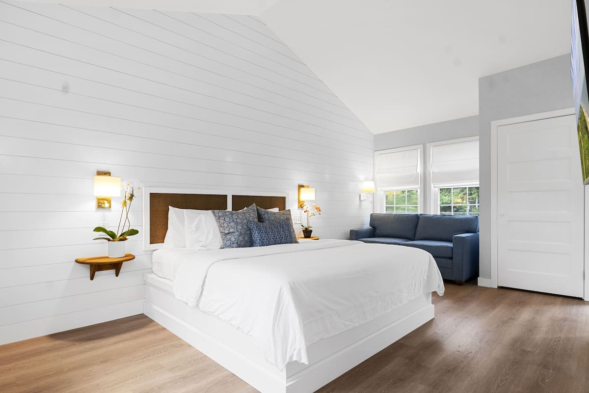 A bedroom with a large bed, a sofa, and a window with a view.