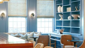 A modern kitchen with a central island, bar stools, and a dining area with wicker chairs.