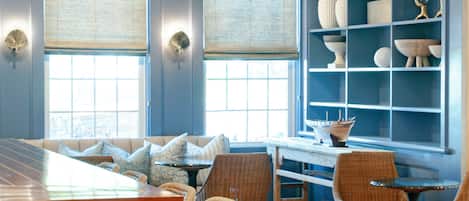 A modern kitchen with a central island, bar stools, and a dining area with wicker chairs.