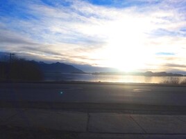 Un atardecer sobre un cuerpo de agua con montañas al fondo.
