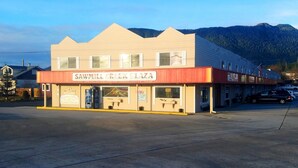 Un edificio de dos pisos con un letrero que dice 'Sawmill Creek Plaza'.