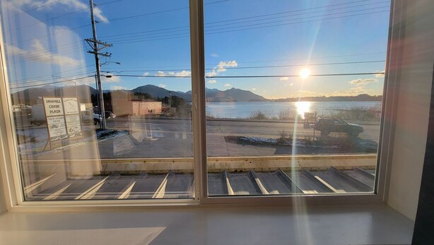 Vista desde una ventana con cielo despejado, montañas y una masa de agua.